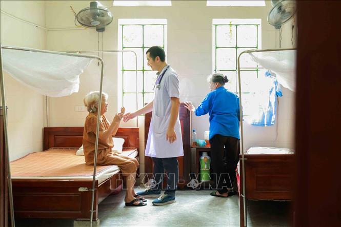 Bác sĩ ân cần trò chuyện, động viên cụ cao tuổi trước giờ dùng thuốc. Ảnh: Hữu Quyết - TTXVN