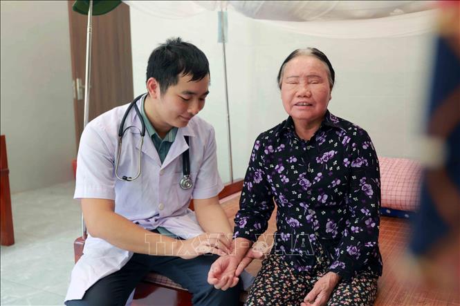 Bác sĩ Đặng Hữu Vũ kiểm tra sức khỏe cho bà Lê Thị Xanh (80 tuổi), thương binh hạng 3/4 (quê xã Cẩm Lạc). Ảnh: Hữu Quyết - TTXVN