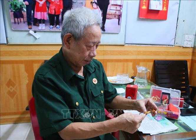 Cựu chiến binh Vũ Doanh Hùng cùng các kỷ vật tại chiến trường năm xưa. Ảnh: Công Luật - TTXVN