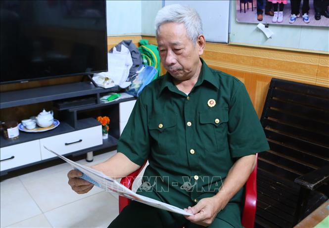 Cựu chiến binh Vũ Doanh Hùng hàng ngày vẫn đọc báo để nắm bắt thông tin. Ảnh: Công Luật - TTXVN