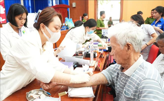 Thực hiện công đoạn lấy mẫu máu thân nhân liệt sĩ để làm công tác giám định ADN. Ảnh: Phan Sáu - TTXVN 