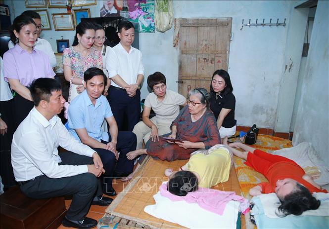 Các đoàn thể, tổ chức, cá nhân thăm hỏi, tặng quà bà Hoàng Thị Gấm ở tổ dân phố Cốc Hạ, phường Đông Hương, đang nuôi dưỡng 2 con gái là nạn nhân chất độc da cam bị nhiễm từ người chồng đi bộ đội ở chiến trường phía Nam (đã mất). Ảnh: Trọng Đức - TTXVN