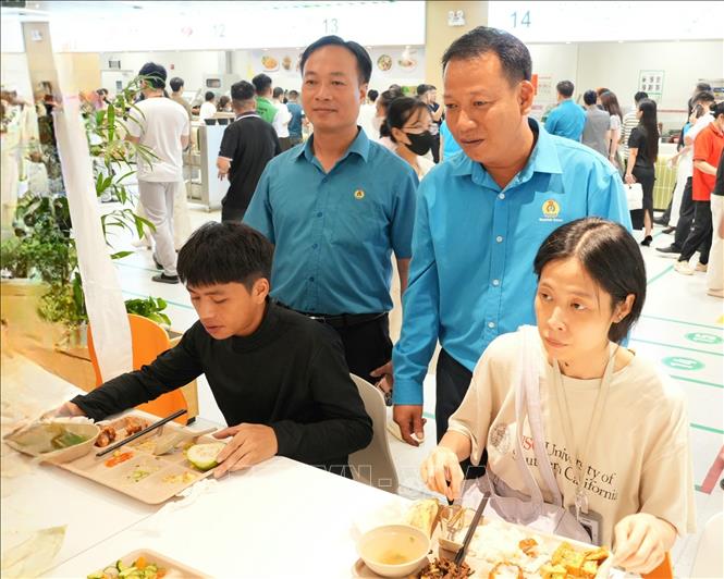 Anh Phạm Văn Trung (bên phải) cùng cán bộ Liên đoàn Lao động tỉnh Bắc Ninh nắm bắt ý kiến công nhân về chất lượng bữa ăn ca tại công ty. Ảnh: Đồng Thúy - TTXVN