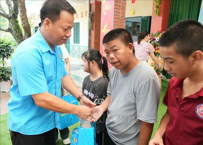 Anh Phạm Văn Trung, Chủ tịch Công đoàn Công ty TNHH Khoa học Kỹ thuật Goertek Vina, trao quà cho trẻ khuyết tật trong hoạt động an sinh xã hội do Công đoàn công ty tổ chức. Ảnh: Đồng Thúy - TTXVN