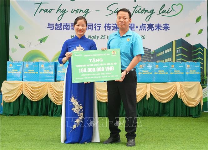 Anh Phạm Văn Trung, Chủ tịch Công đoàn Công ty TNHH Khoa học Kỹ thuật Goertek Vina, trao biển tượng trưng kinh phí hỗ trợ Trường Giáo dục trẻ khuyết tật Sóc Sơn trong hoạt động an sinh xã hội. Ảnh: Đồng Thúy - TTXVN