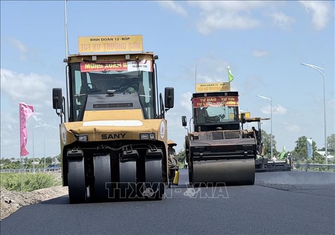 Xe thảm nhựa và các phương tiện thi công hoạt động liên tục trên đường dẫn vào tuyến cao tốc Châu Đốc - Cần Thơ - Sóc Trăng đoạn qua phường Vĩnh Tế, An Giang. Ảnh: Thanh Sang - TTXVN