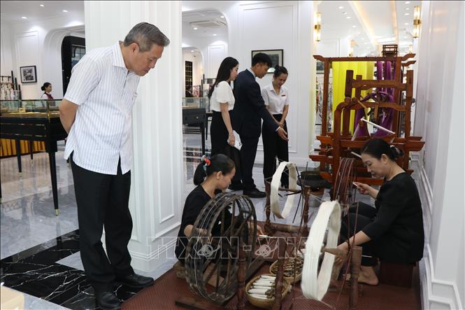 Du khách dõi theo các thao tác dệt lụa tơ tằm thủ công của các nghệ nhân. Ảnh: Mai Trang - TTXVN 