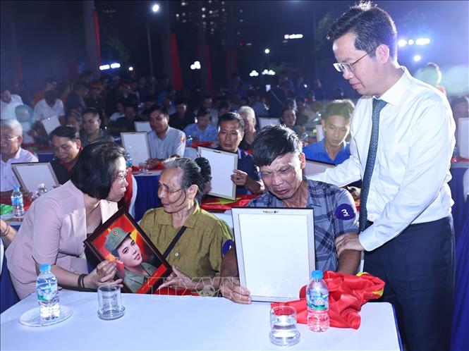 Các gia đình, thân nhân các anh hùng liệt sĩ xúc động đón nhận di ảnh phục dựng. Ảnh: Minh Đức - TTXVN