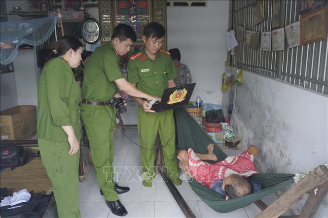 Cán bộ, chiến sĩ thực hiện thủ tục chụp ảnh để làm căn cước cho người già yếu tại xã Đá Bạc (tỉnh Cà Mau). Ảnh: TTXVN phát.
