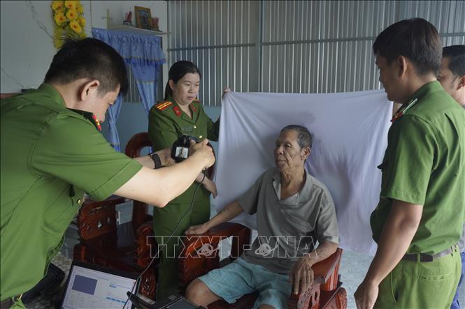 Cán bộ, chiến sĩ thực hiện thủ tục chụp ảnh để làm căn cước cho người già yếu tại xã Đá Bạc (tỉnh Cà Mau). Ảnh: TTXVN phát