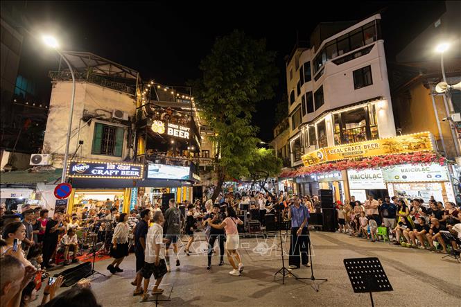 Biểu diễn âm nhạc đường phố sôi động, hiện đại tại khu vực giao lộ Phố cổ Hà Nội. Các đêm nhạc ngẫu hứng cuối tuần không chỉ làm phong phú thêm sản phẩm du lịch đêm mà còn tạo điểm nhấn không gian văn hóa mở, thu hút du khách trong và ngoài nước hòa mình vào nhịp sống trẻ trung của Thủ đô. Ảnh: Tiến Long/TTXVN phát

