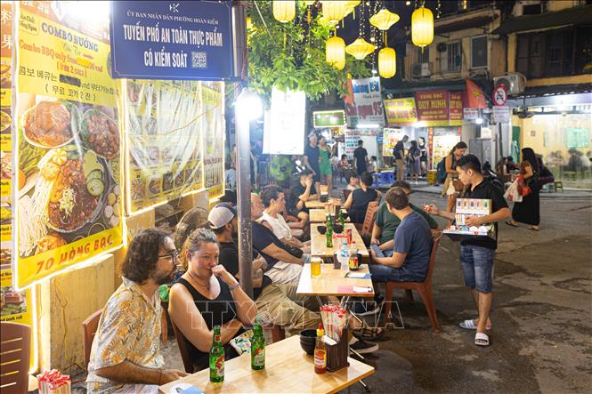 Du khách quốc tế thưởng thức ẩm thực đường phố tại khu vực được gắn biển 