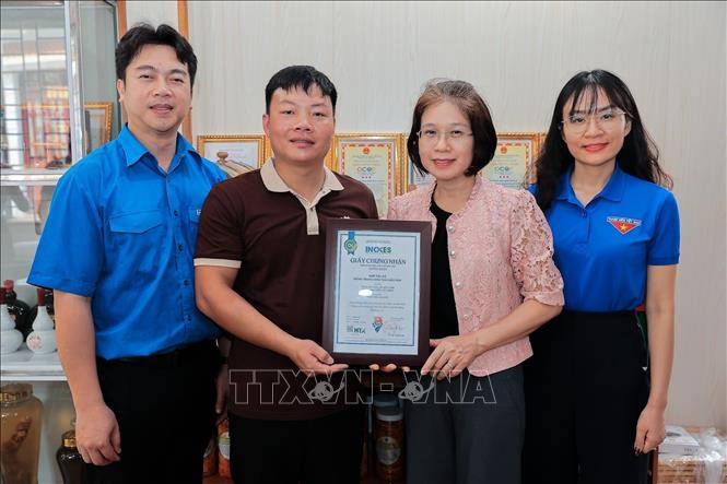 Bà Nguyễn Thị Hoài Linh, Phó Chủ tịch Liên minh Hợp tác xã Việt Nam trao Giấy chứng nhận sản phẩm “Rượu men lá A Múi” của HTX Nông trang sinh thái Mẫu Sơn thực hiện Truy xuất nguồn gốc trên hệ thống hoptaxa.vn. Ảnh: Lê Đông - TTXVN