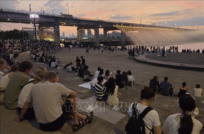 Người dân tận hưởng không khí dịu mát bên hệ thống phun nước trên cầu Banpo sau khi thủ đô Seoul (Hàn Quốc) ban hành cảnh báo đêm nhiệt đới, ngày 12/7/2026. Ảnh: Yonhap/TTXVN phát