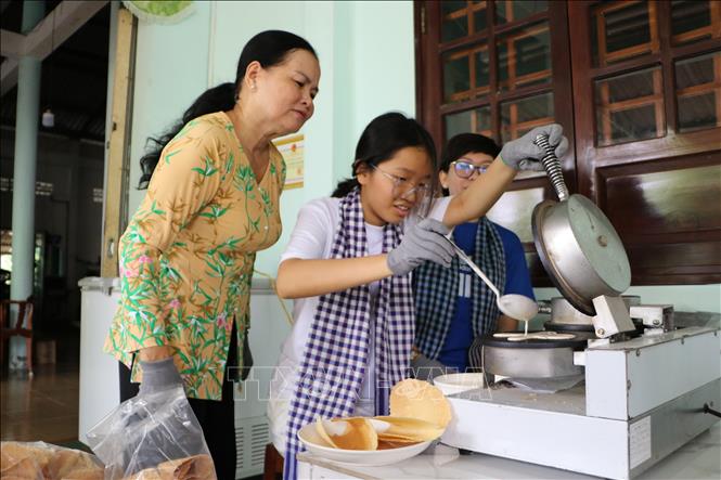 Du khách trải nghiệm làm bánh kẹp xoài tại Di tích Phủ thờ Thư Ngọc Hầu (xã Mỹ Thọ). Ảnh: Hồng Thái - TTXVN
