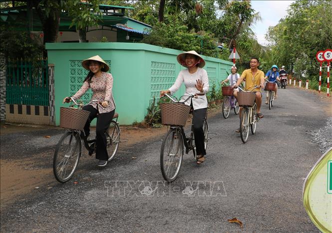 Du khách trải nghiệm di chuyển đến các điểm du lịch bằng xe đạp tại xã Mỹ Thọ. Ảnh: Hồng Thái - TTXVN