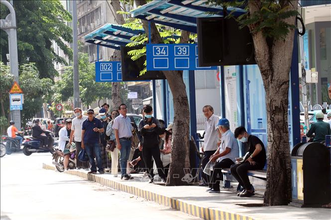 Hành khách chờ xe buýt tại trạm sáng 30/7/2026. Ảnh: Tiến Lực - TTXVN