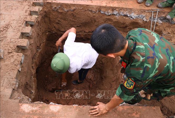 Lực lượng khai quật tiến hành phá dỡ nhiều lớp đất đá để tiếp cận được hài cốt liệt sĩ tại Nghĩa trang liệt sĩ Ngọc Hồi (xã Thanh Trì). Ảnh: Văn Điệp – TTXVN