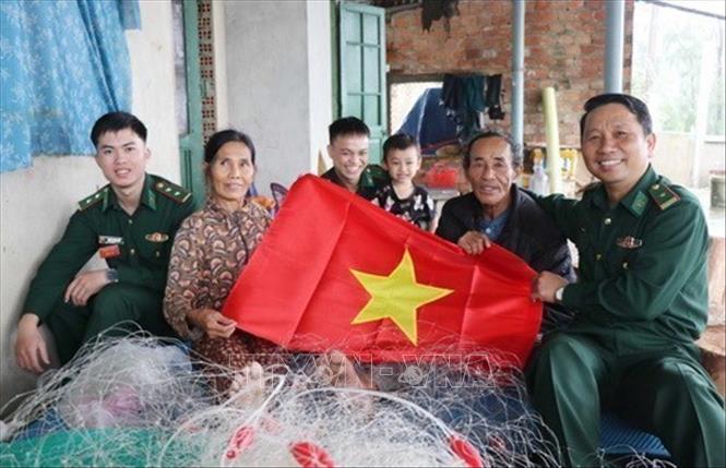 Cán bộ Đồn biên phòng Cửa khẩu Cảng Dung Quất trao cờ Tổ quốc và tuyên truyền về chủ quyền biển, đảo cho ngư dân thôn Tuyết Diêm 1, xã Bình Thuận, huyện Bình Sơn (Quảng Ngãi), 2024. Ảnh: Phạm Cường - TTXVN