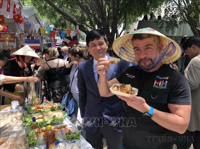 Đại sứ Việt Nam Nguyễn Hoành Năm giới thiệu tới Chủ tịch quận Mauricio Tabe Echartea món nem rán của Việt Nam tại Lễ hội văn hóa và ẩm thực Bazaar ASEAN+3, được tổ chức tại thành phố Mexico City (8/8/2022). Ảnh: Lưu Việt Hùng - TTXVN