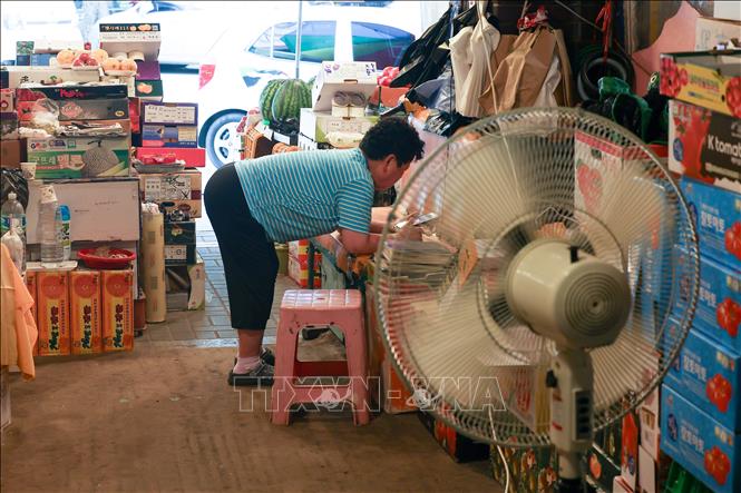 Người dân dùng quạt điện để tránh nóng tại Seoul, Hàn Quốc. Ảnh: Yonhap/TTXVN phát