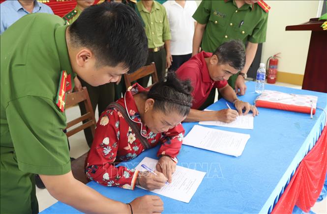 Cán bộ Công an xã Yên Na (Nghệ An) hướng dẫn người dân hoàn thiện các thủ tục ký cam kết chấp hành pháp luật, không khai thác vàng trái phép tại khu vực khe Huổi Lúc và các địa bàn lân cận. Ảnh: Văn Tý - TTXVN
