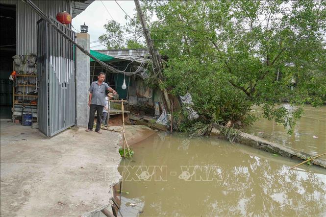Ông Trần Văn Sang, chủ cửa hàng kinh doanh gas ở ấp Mang Cá, xã Đại Hải đứng trước cửa ngôi nhà đã bị sạt lở vào tận cửa ra vào. Ảnh: Thanh Liêm - TTXVN