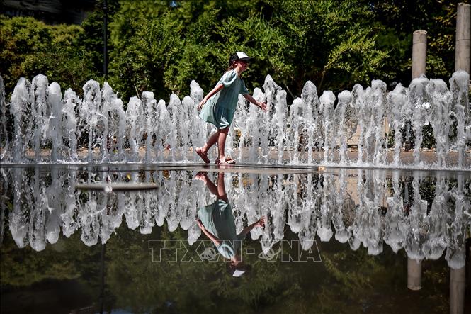 Em nhỏ chơi đùa bên đài phun nước để tránh nóng tại Budapest, Hungary. Ảnh: THX/TTXVN phát