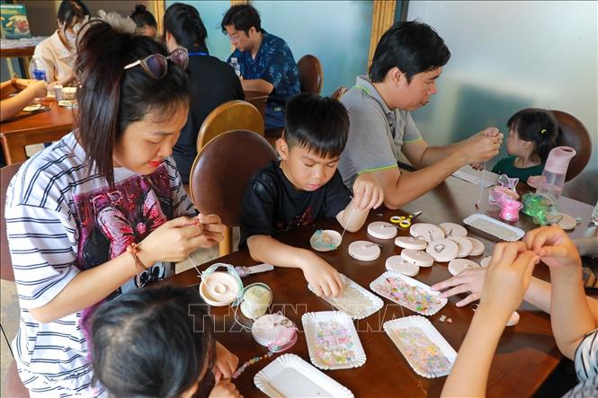 Hoạt động trải nghiệm trang trí nón quai thao thu hút sự tham gia của người dân. Ảnh: Khánh Hoà - TTXVN