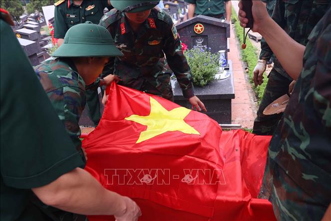 Thực hiện nghi thức phủ Quốc kỳ trang trọng, tri ân Anh hùng liệt sĩ đã hy sinh vì độc lập, tự do của Tổ quốc tại Nghĩa trang liệt sĩ Nhổn (phường Tây Tựu). Ảnh: Văn Điệp – TTXVN