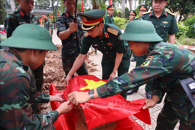Thực hiện nghi thức phủ Quốc kỳ trang trọng, tri ân Anh hùng liệt sĩ đã hy sinh vì độc lập, tự do của Tổ quốc tại Nghĩa trang liệt sĩ Nhổn (phường Tây Tựu). Ảnh: Văn Điệp – TTXVN