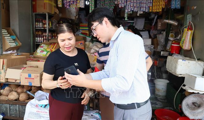 Nhân viên VNPT Đồng Nai hướng dẫn tiểu thương Chợ Đồng Xoài cài đặt, sử dụng các ứng dụng số, từng bước đưa hoạt động kinh doanh lên môi trường số. Ảnh: Đậu Tất Thành – TTXVN