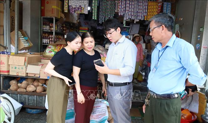 Nhân viên VNPT Đồng Nai trao đổi, giới thiệu các tiện ích của nền tảng số, hỗ trợ tiểu thương làm quen với phương thức kinh doanh trên môi trường trực tuyến tại Chợ Đồng Xoài. Ảnh: Đậu Tất Thành – TTXVN