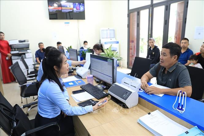 Cán bộ Điểm hỗ trợ dịch vụ công số Thư Lâm hướng dẫn người dân hoàn thiện hồ sơ, thủ tục hành chính. Ảnh: Trung Nguyên - TTXVN