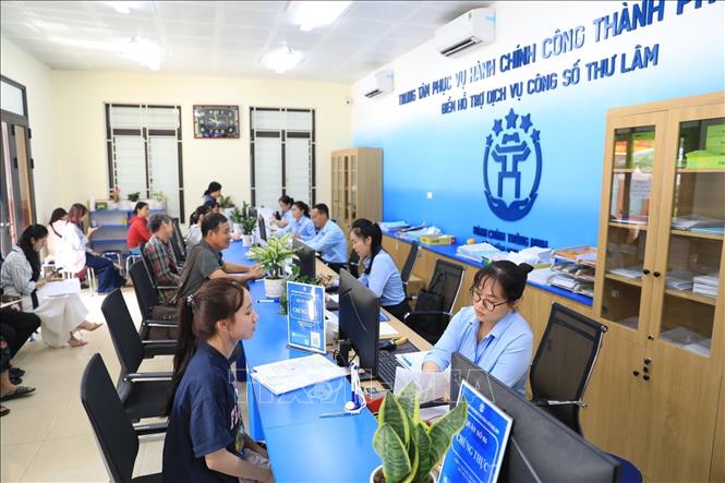 Cán bộ Điểm hỗ trợ dịch vụ công số Thư Lâm tiếp nhận, giải quyết thủ tục hành chính cho người dân. Ảnh: Trung Nguyên - TTXVN