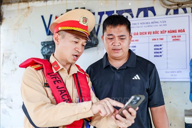 Cán bộ Đội Cảnh sát đường thủy số 2 hướng dẫn đại diện Bến thủy nội địa Hồng Vân tra cứu vị trí, thông tin trên bản đồ đường thủy online. Ảnh: Trung Nguyên - TTXVN