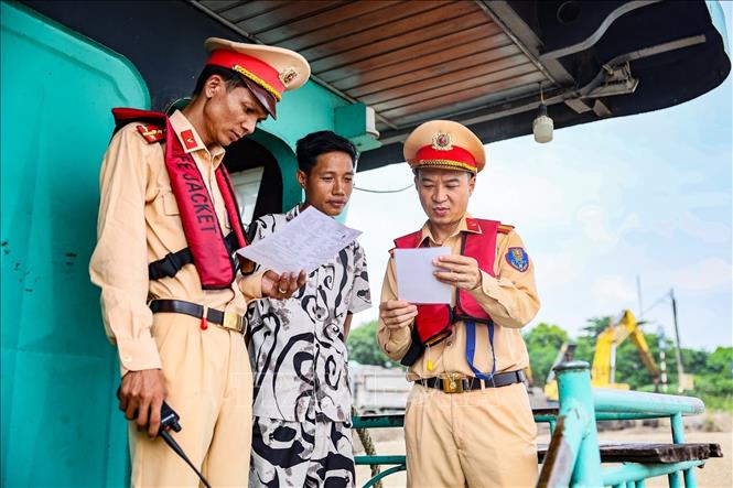 Cán bộ Đội Cảnh sát đường thủy số 2 tuyên truyền, hướng dẫn người điều khiển phương tiện chấp hành các quy định về trật tự, an toàn giao thông đường thủy nội địa. Ảnh: Trung Nguyên - TTXVN