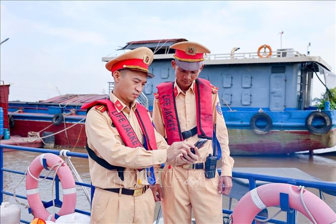 Cán bộ Đội Cảnh sát đường thủy số 2 sử dụng bản đồ đường thủy online để xác định vị trí bến, bãi trong quá trình tuần tra trên tuyến. Ảnh: Trung Nguyên - TTXVN