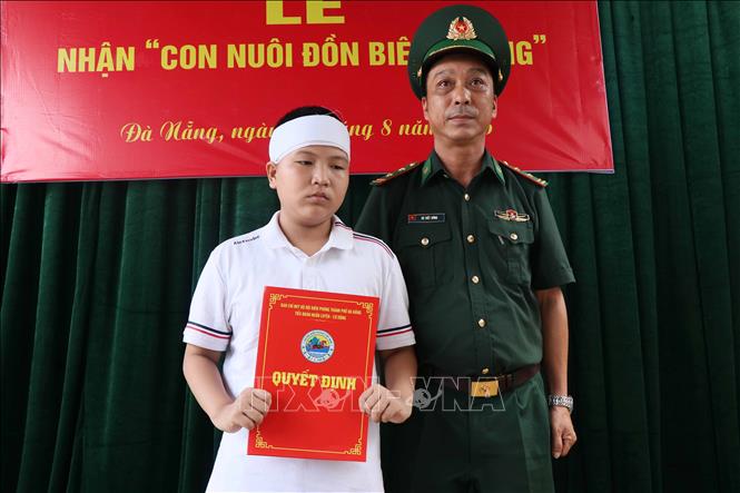 Chỉ huy Tiểu đoàn Huấn luyện - Cơ động, thuộc Ban chỉ huy Bộ đội biên phòng thành phố Đà Nẵng trao Quyết định nhận làm con nuôi cho cháu Lê Viết Hồng Pháp. Ảnh: Đoàn Hữu Trung - TTXVN