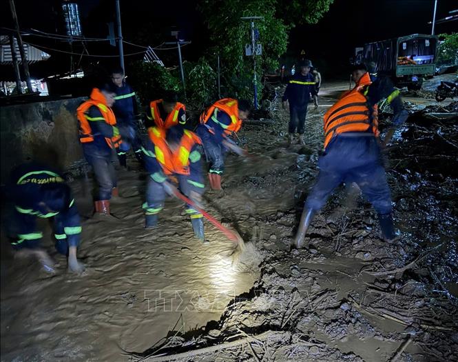 Lực lượng chức năng tỉnh Sơn La dọn bùn đất tràn xuống Quốc lộ 6 đoạn thuộc địa phận xã Muổi Nọi. Ảnh: TTXVN phát