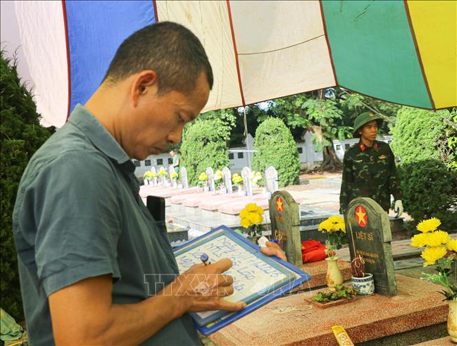 Lực lượng chức năng cẩn trọng ghi chép thông tin tromg quá trình khai quật các phần mộ tại Nghĩa trang Liệt sĩ Độc Lập, xã Thanh Nưa. Ảnh: Phan Quân - TTXVN