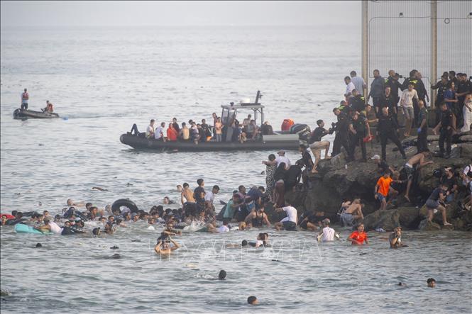 Trong số khoảng 60.000 người tìm cách vượt biên sang Ceuta, vùng lãnh thổ của Tây Ban Nha ở Bắc Phi, có hơn 800 trẻ vị thành niên không có người thân đi cùng, đang phải chờ được tiếp nhận và hỗ trợ theo quy định của Tây Ban Nha. Tình trạng này xảy ra sau làn sóng vượt biên quy mô lớn từ Maroc, làm gia tăng sức ép nhân đạo đối với tuyến biên giới châu Phi - châu Âu. Trong ảnh: Người di cư tìm cách bơi từ Maroc sang Ceuta (Tây Ban Nha), ngày 30/7/2026. Ảnh: AA/TTXVN phát