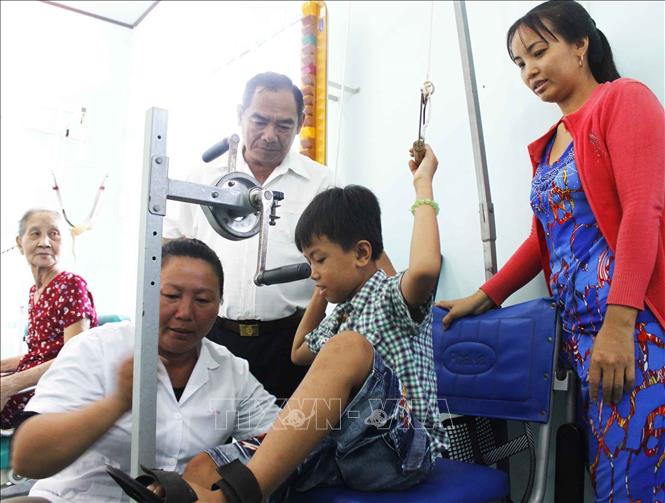 Ngày 22/4/2017, Hội nạn nhân chất độc da cam/dioxin tỉnh Vĩnh Long phối hợp với nhà tài trợ trao tặng bộ dụng cụ tập luyện cho Trung tâm phục hồi chức năng nạn nhân chất độc da cam/dioxin huyện Tam Bình, tỉnh Vĩnh Long. Với tổng giá trị trên 40 triệu đồng. Trong ảnh: Đại diện nhà tài trợ thăm và hướng dẫn trẻ luyện tập phục hồi chức năng. Ảnh: Lê Thúy Hằng - TTXVN 
