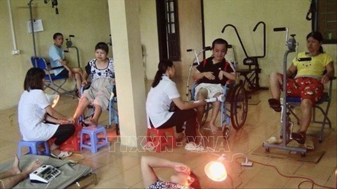 Cán bộ Trung tâm Chăm sóc nuôi dưỡng và Điều trị nạn nhân bị nhiễm chất độc da cam/dioxin Hà Nội chăm sóc, điều trị cho các nạn nhân chất độc da cam/dioxin. Ảnh: TTXVN phát 
