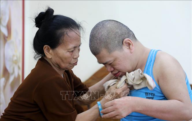 Dù tuổi đã cao nhưng bà Phạm Thị Lán (thôn Thượng Bái xã Diên Hà, tỉnh Hưng Yên) hàng ngày vẫn phải chăm sóc con trai bị ảnh hưởng bởi chất độc da cam/dioxin nằm liệt giường đã 41 năm nay. Ảnh: Thế Duyệt - TTXVN
