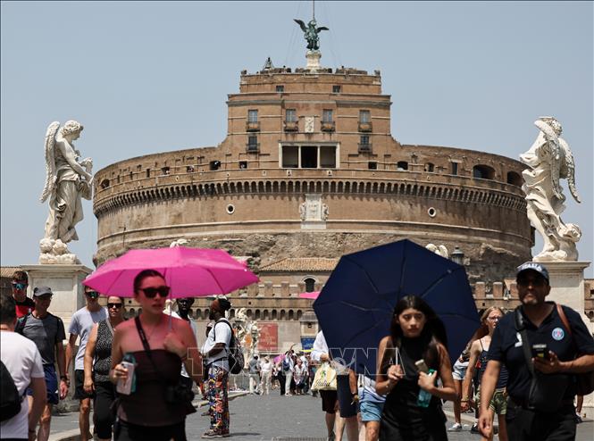 Du khách che ô tránh nắng khi di chuyển trên cầu Ponte Sant'Angelo ở Rome, Italy, ngày 19/7/2026. Ảnh: THX/TTXVN phát
