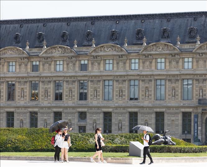 Khách du lịch che ô tránh nắng nóng tại Paris, Pháp. Ảnh: THX/TTXVN phát