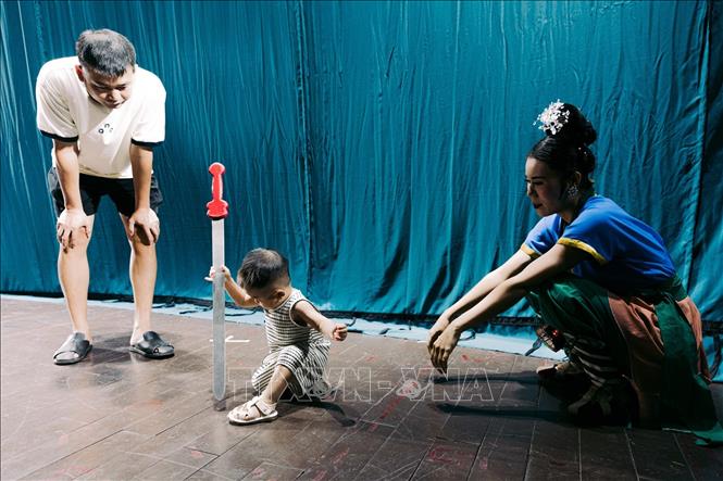Một em nhỏ thích thú làm quen với đạo cụ biểu diễn dưới sự hướng dẫn của nghệ sĩ. Việc tạo điều kiện để nhiều lứa tuổi trực tiếp trải nghiệm là một cách mở rộng công chúng cho sân khấu truyền thống. Ảnh: Phạm Tuấn Anh - TTXVN