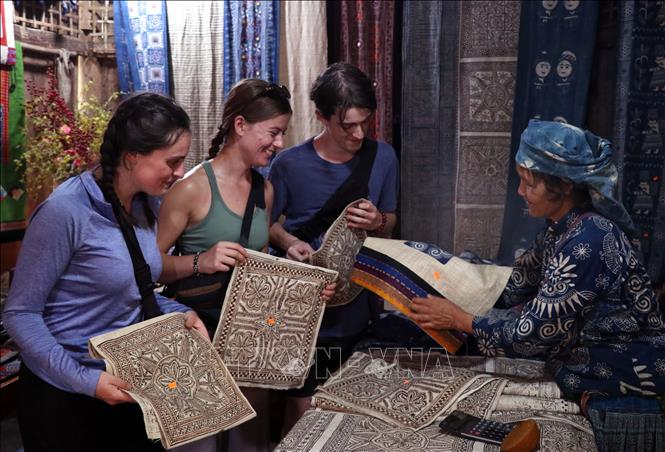 Du khách nước ngoài thích thú khám phá các sản phẩm dệt lanh truyền thống của đồng bào Mông ở Lùng Tám (Tuyên Quang). Ảnh: Đức Thọ - TTXVN
