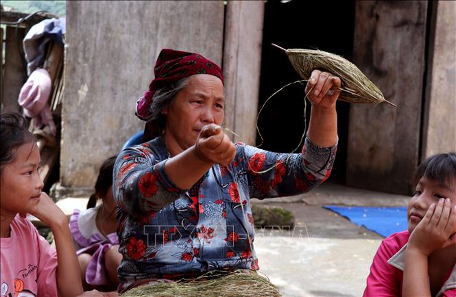Các cháu nhỏ ở Lùng Tám (Tuyên Quang) ngồi xem nghệ nhân se những sợi lanh truyền thống . Ảnh: Đức Thọ - TTXVN